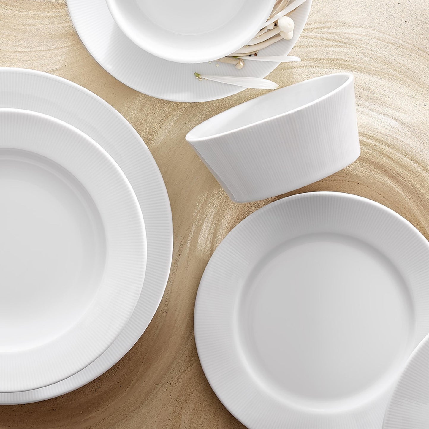 Set of white ceramic plates and bowls on a wooden surface