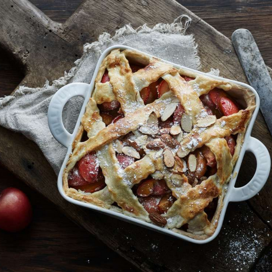 Baked pie with lattice crust in a white dish on a wooden surface