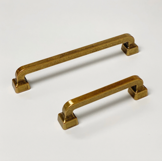 Two brass cabinet handles on a white background