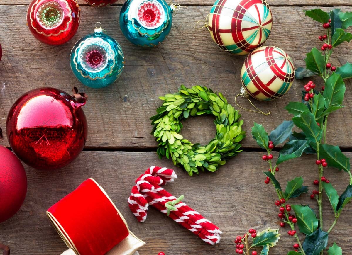 Christmas ornaments including red and green baubles, a candy cane, and holly leaves on a wooden surface.