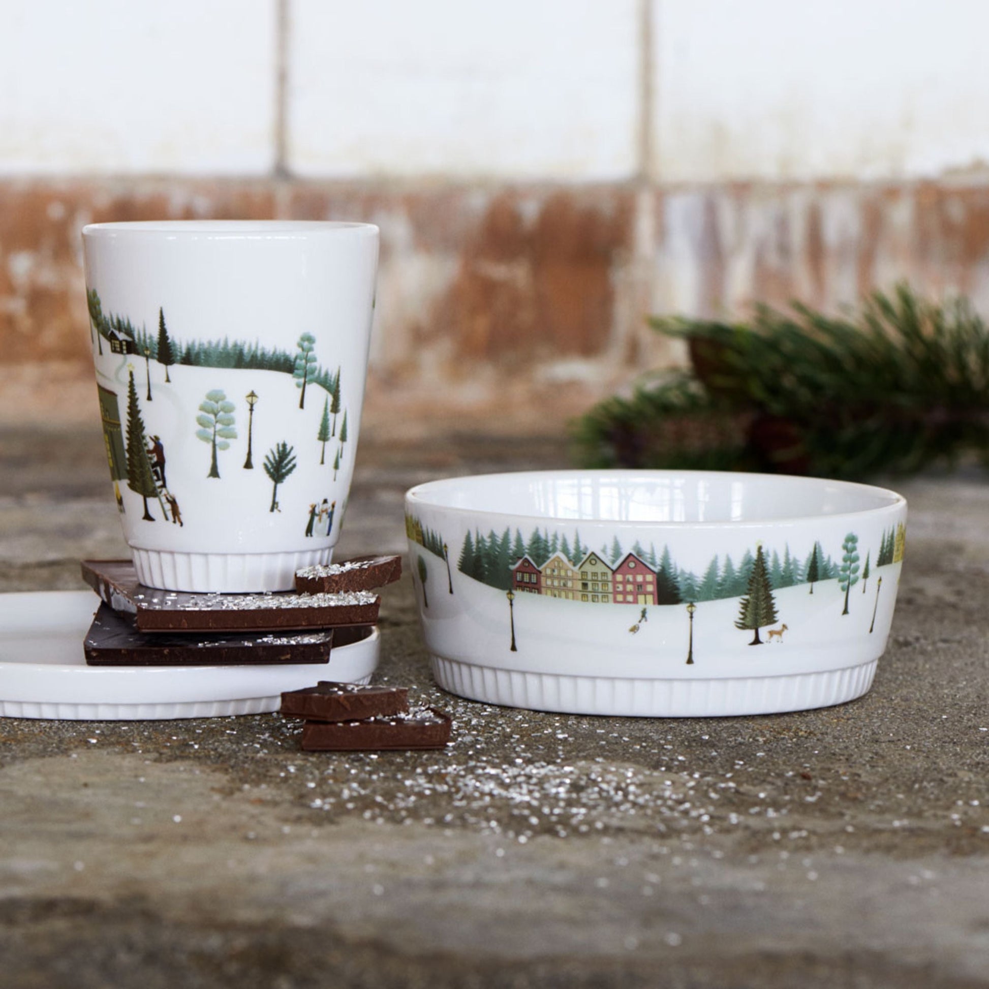 Ceramic cup and bowl with nature-themed design on a stone surface