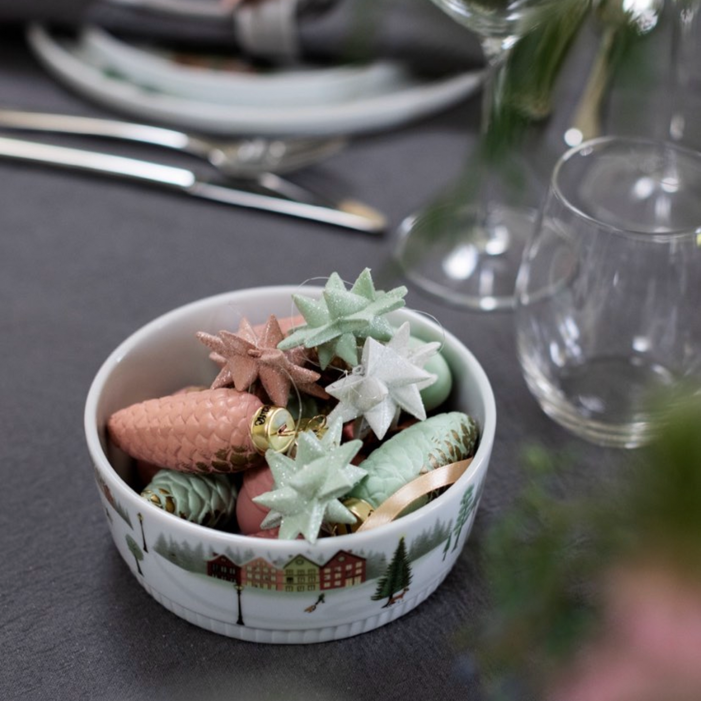 Decorative bowl with Christmas-themed figurines on a table setting.