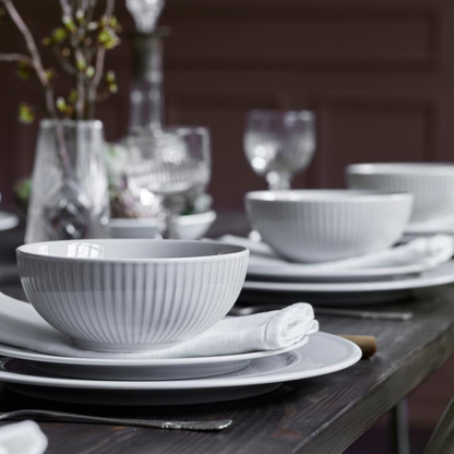 Dining table setting with gray bowls and plates on a dark surface.