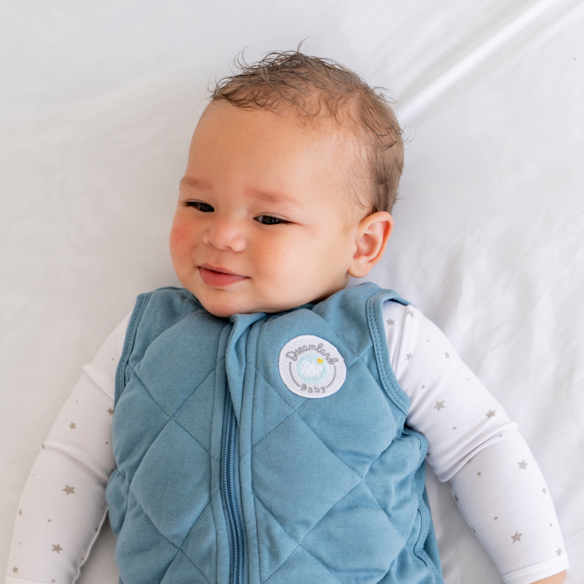 Baby wearing a blue quilted vest with a visible brand logo on a white background