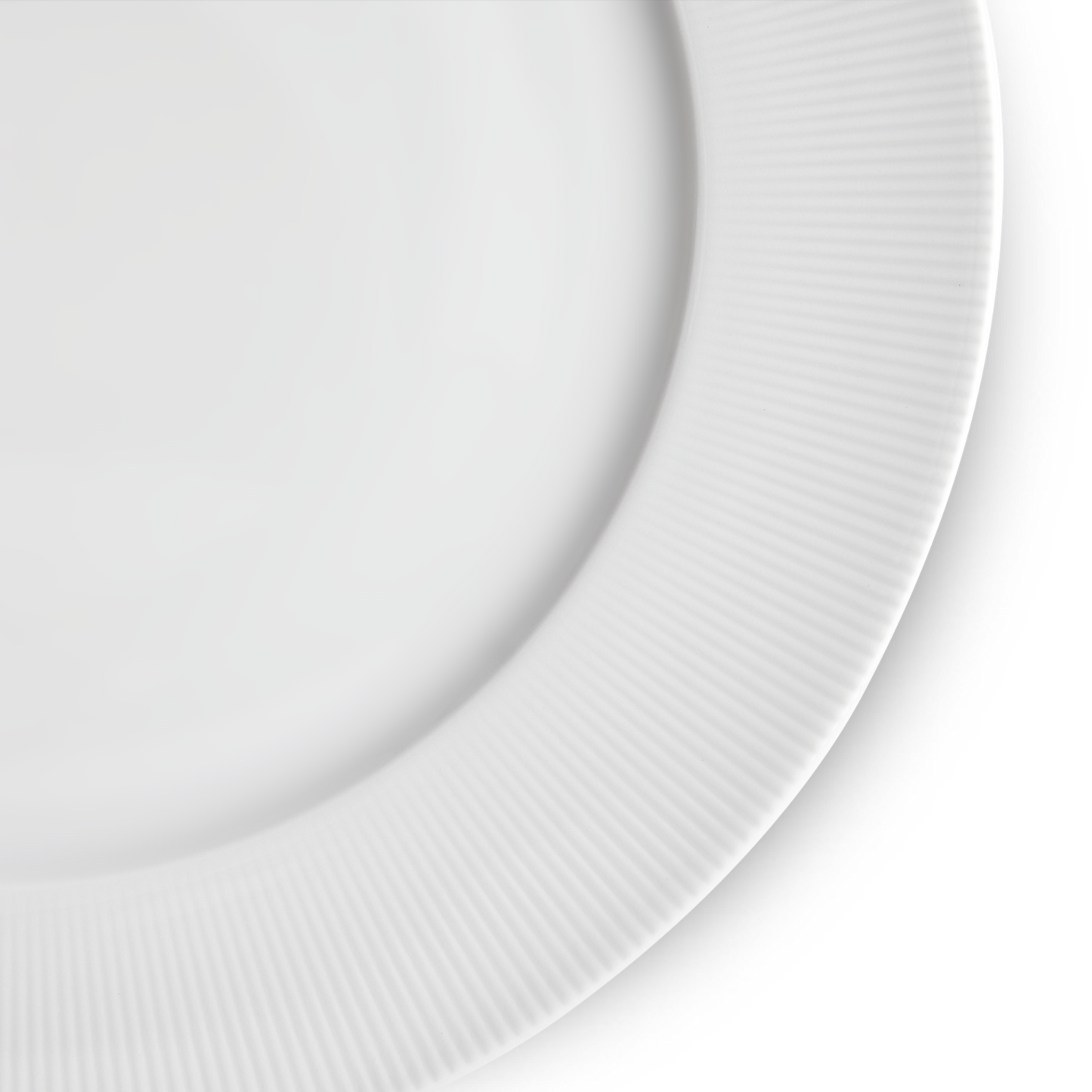 Close-up of a white ceramic plate with a ribbed texture on a light gray background