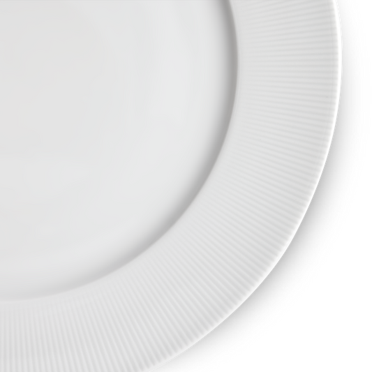 Close-up of a white ceramic plate with a ribbed texture on a light gray background