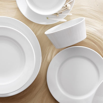 Set of white ceramic plates and bowls on a wooden surface
