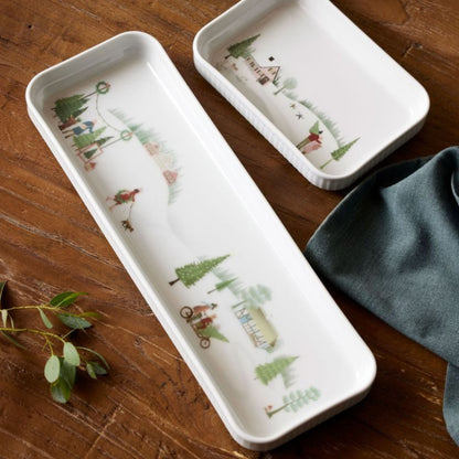 Two ceramic trays with nature-themed designs on a wooden surface.