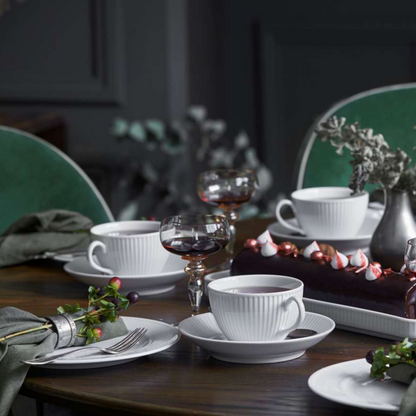 Dining table set with white cups, saucers, and a chocolate cake with candy canes.