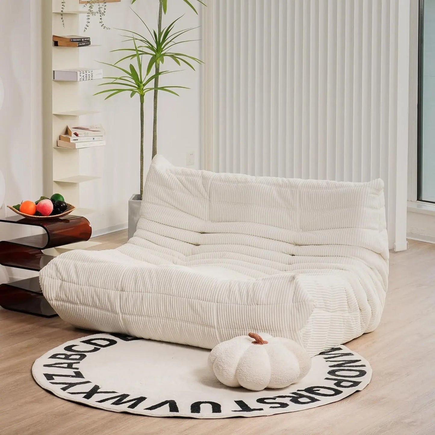 Ivory corduroy bean bag loveseat sofa with low-profile design, styled in a bright, minimalist interior.