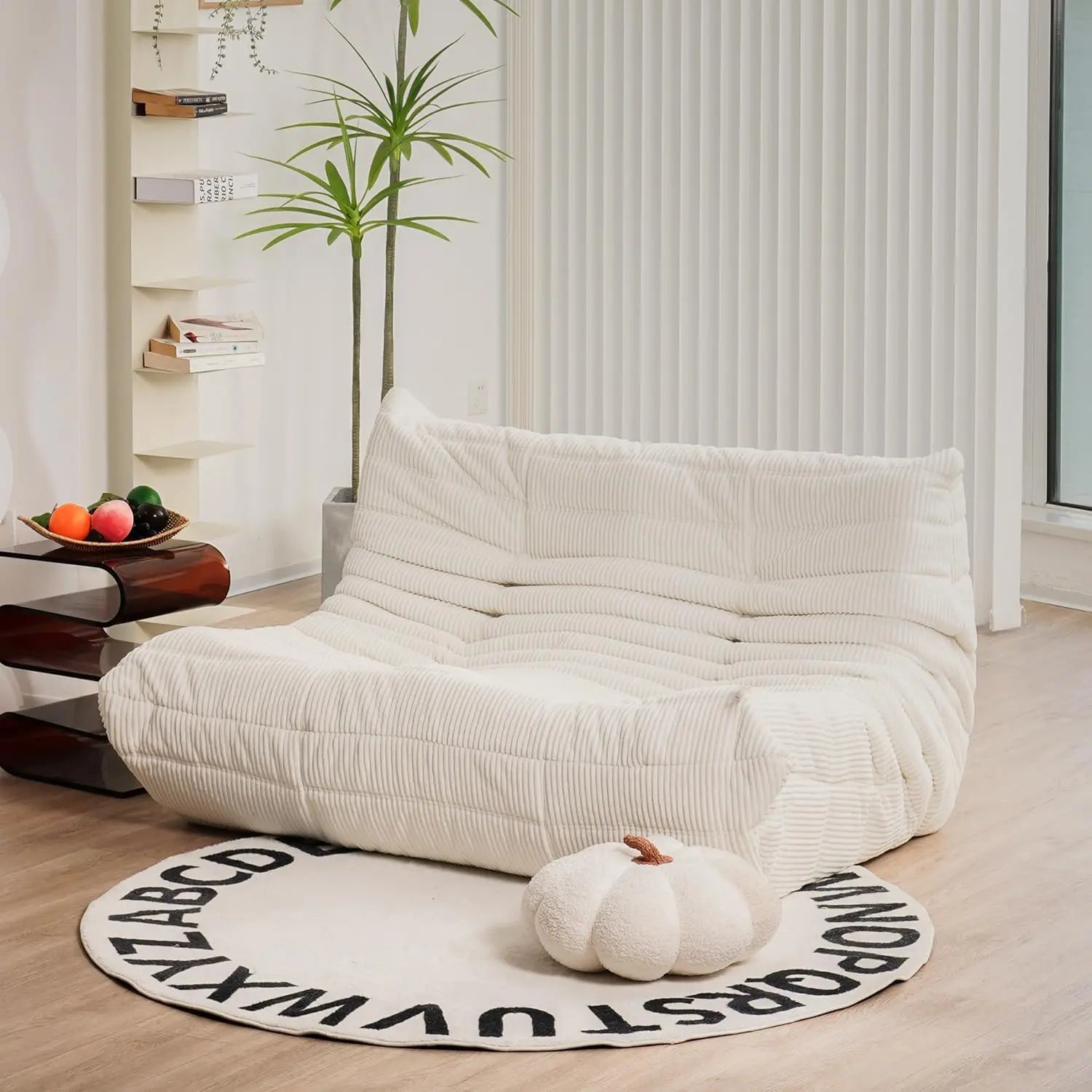 Ivory corduroy bean bag loveseat sofa with low-profile design, styled in a bright, minimalist interior.