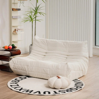 Ivory corduroy bean bag loveseat sofa with low-profile design, styled in a bright, minimalist interior.