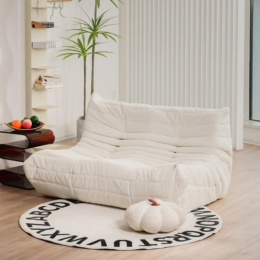 Ivory corduroy bean bag loveseat sofa with low-profile design, styled in a bright, minimalist interior.