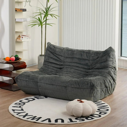 Dark Grey corduroy bean bag loveseat sofa styled in a cozy living room with warm wood tones and soft textures.