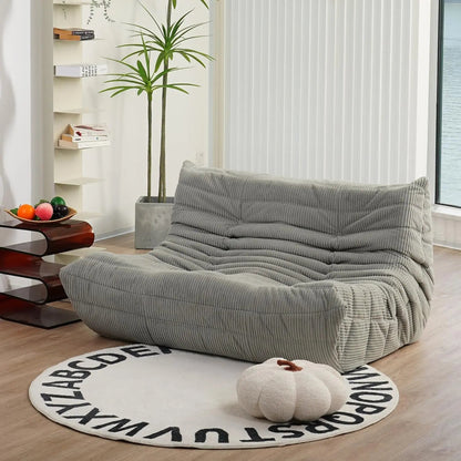 Light grey bean bag loveseat sofa in textured corduroy fabric, modern lounge seating for contemporary living spaces.