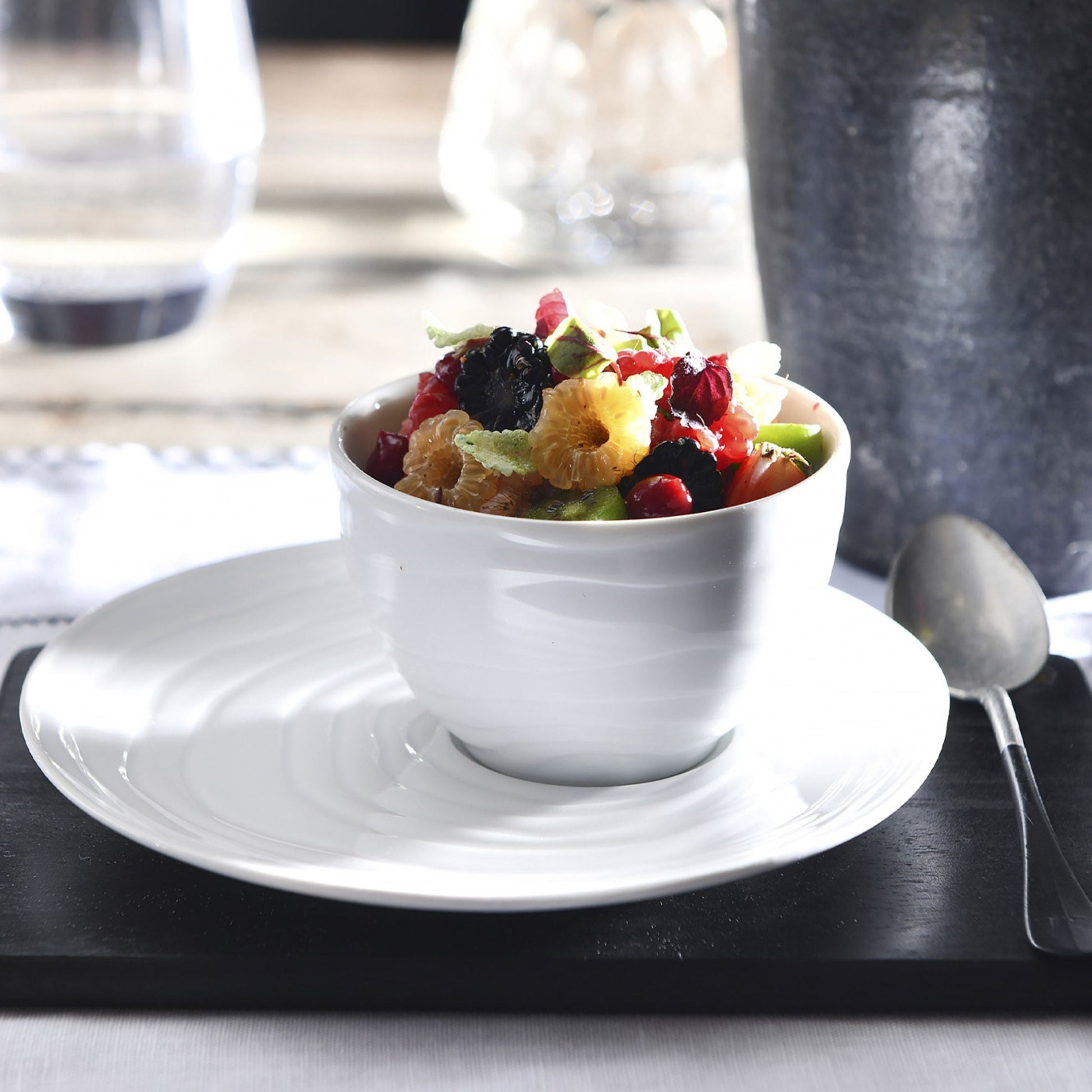 White bowl with fruit salad on a white plate with a blurred background