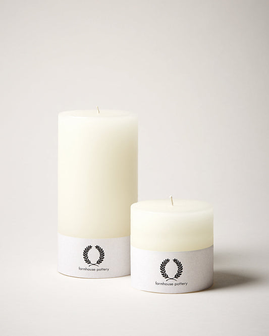 Two white candles with labels on a light gray background