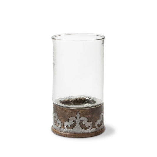 Clear glass candle holder with decorative metal base on a white background of a fleur de lis and scrolls. simply beautiful