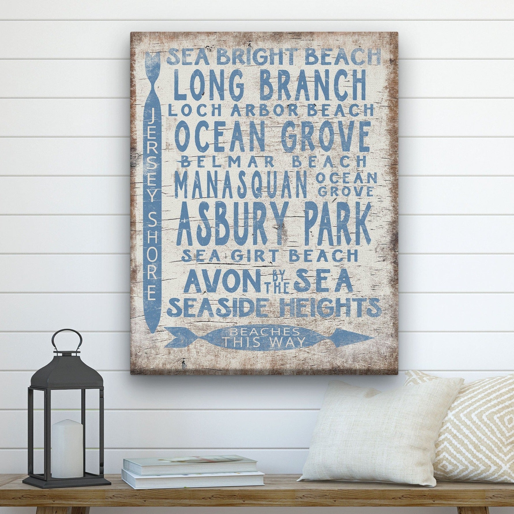 Decorative sign with beach names on a wall above a wooden bench.
