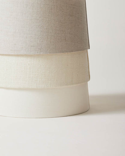 Close-up of a lamp with a beige fabric shade on a white background