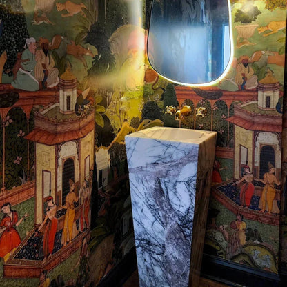 Decorative lamp with marble base against a colorful mural background