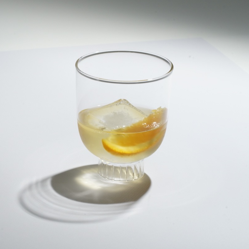 Clear glass with a cocktail and orange slice on a white background