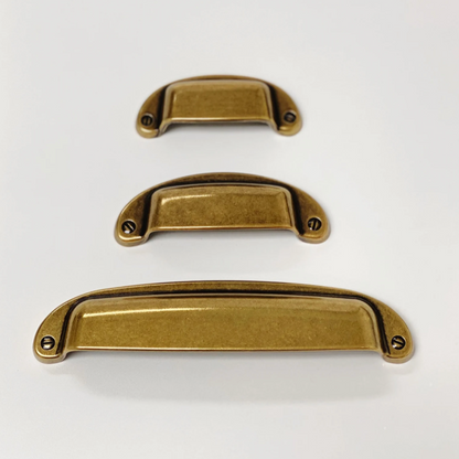 Three brass cabinet handles of different sizes on a white background
