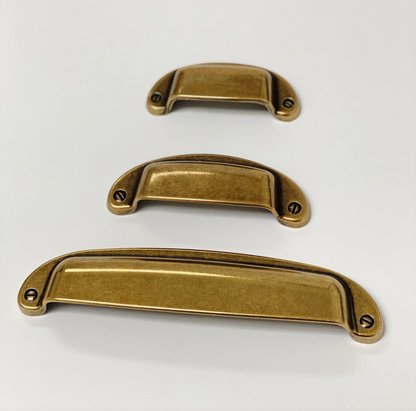 Three brass cabinet handles of different sizes on a white background