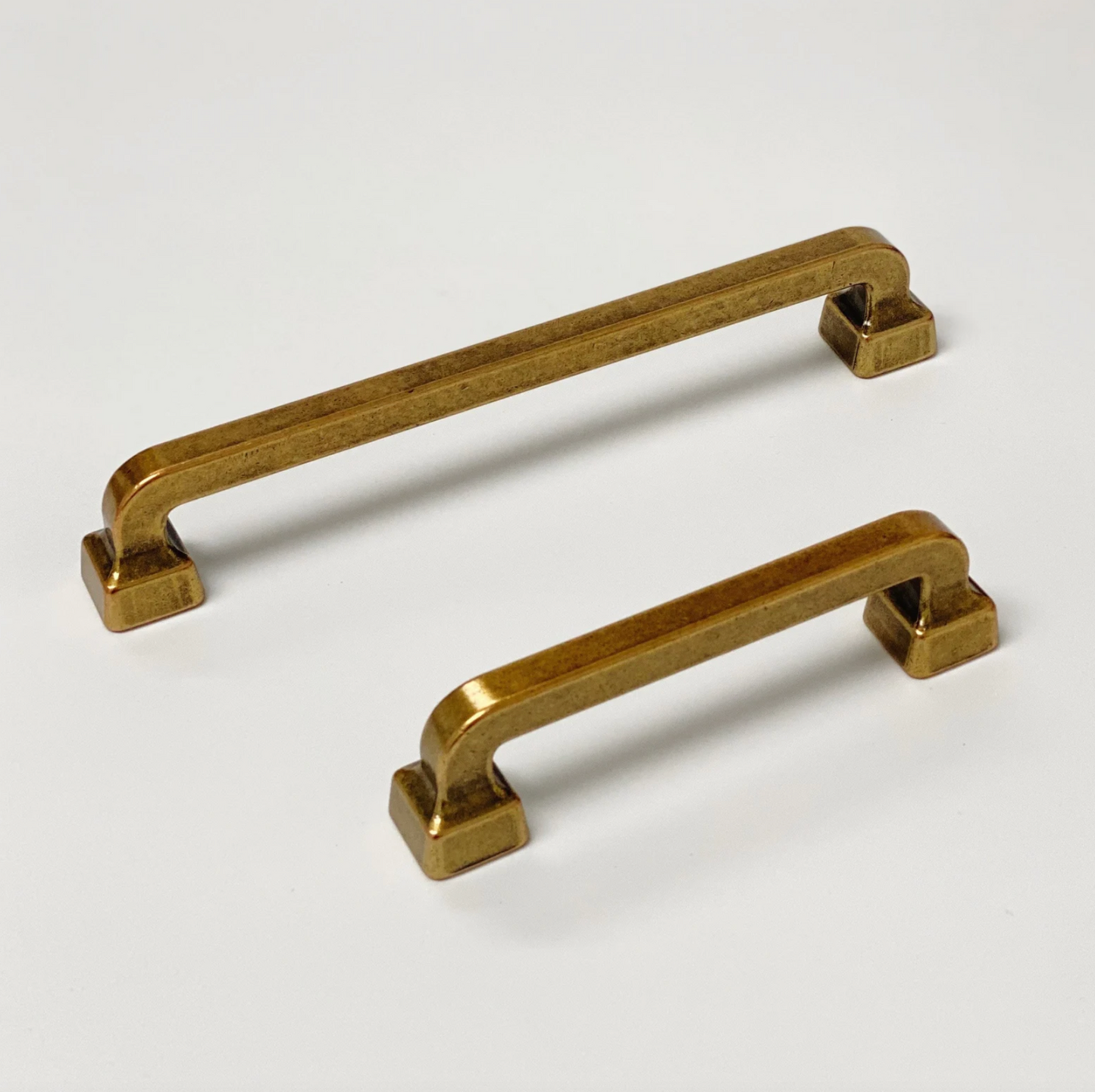 Two brass cabinet handles on a white background