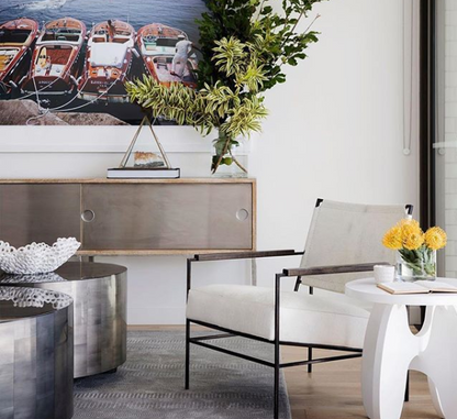 Modern interior with a painting of boats, a chair, and decorative elements.