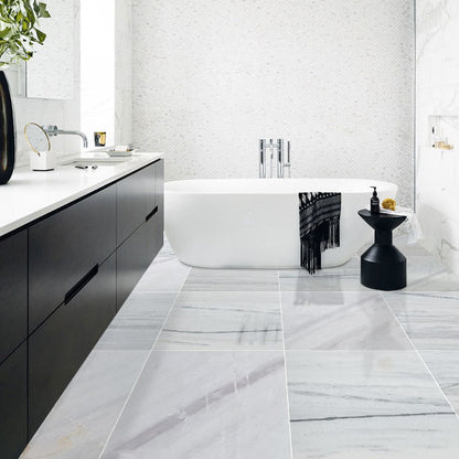 Modern bathroom with marble tiles, black vanity, and white bathtub.