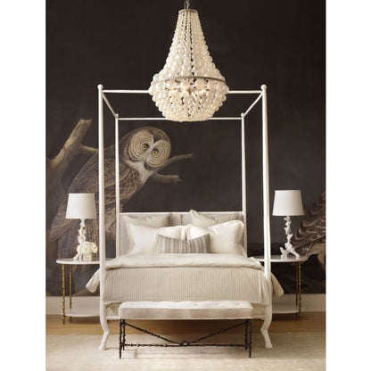 Neoclassical-style bed with white canopy and chandelier in a bedroom setting.