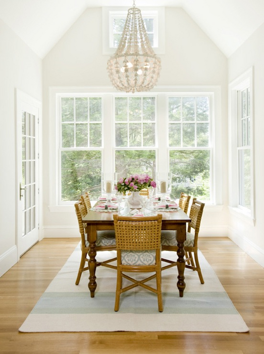 Dining room with wooden table and chairs, large windows, and a chandelier.