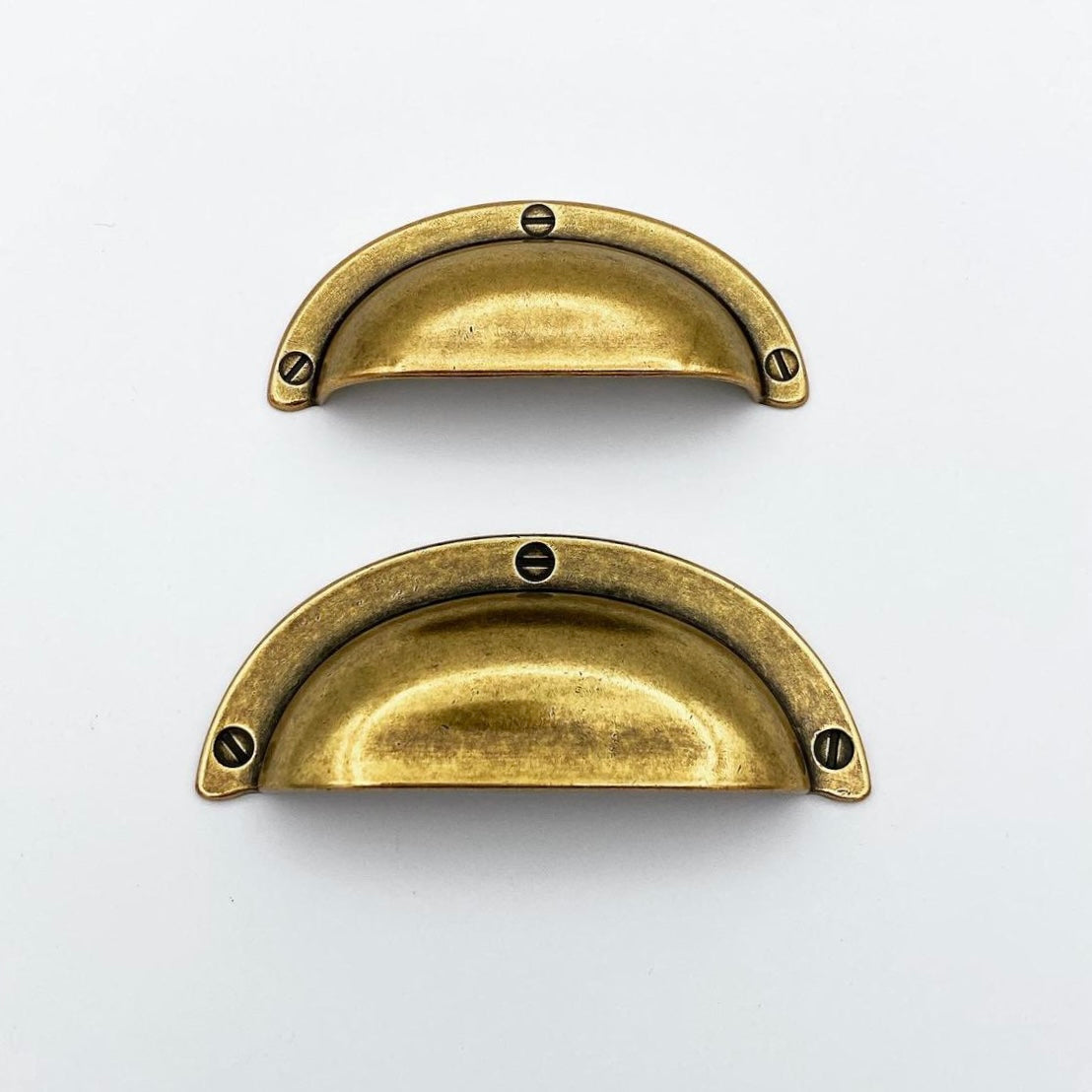 Two brass cabinet handles on a light gray background