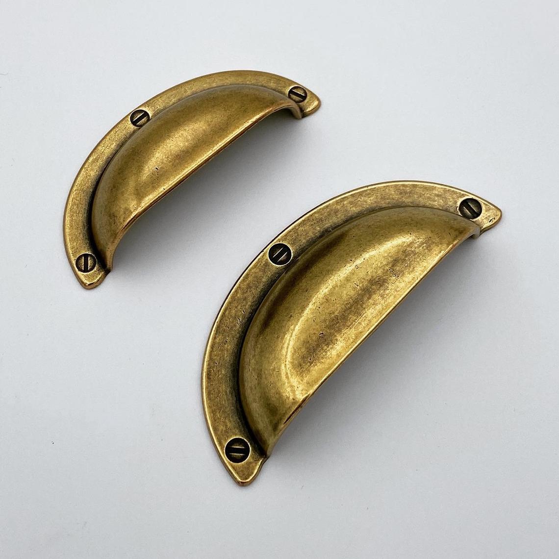 Two brass cabinet handles on a white background