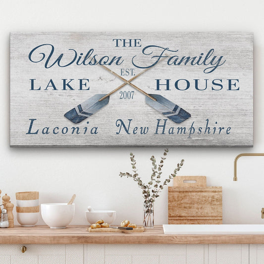 Decorative sign with 'The Wilson Family Lake House' text and oar designs on a wall above a counter.