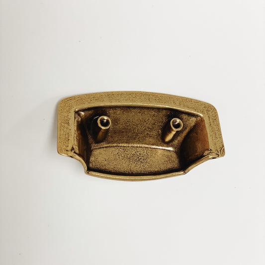 Brass-colored metal bracket on a light gray background