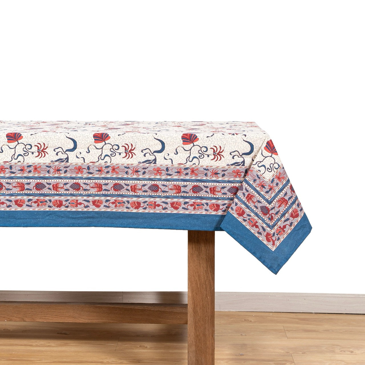 Decorative tablecloth with a pattern on a wooden table against a white wall.