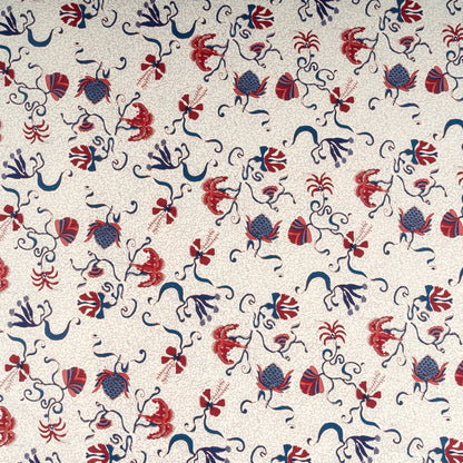 Patterned fabric with red, blue, and black floral and abstract designs on a beige background