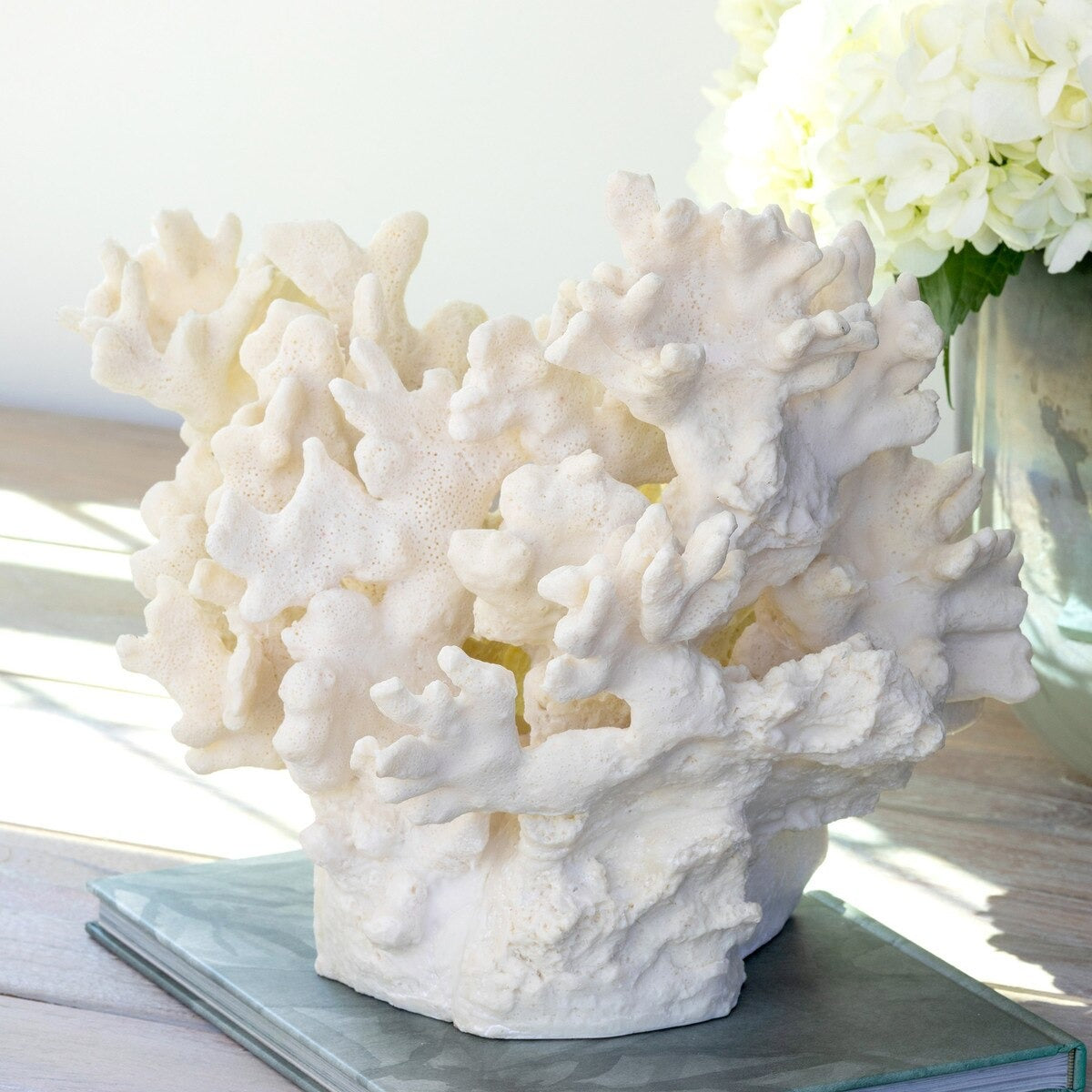 White coral sculpture on a table with a vase of flowers in the background