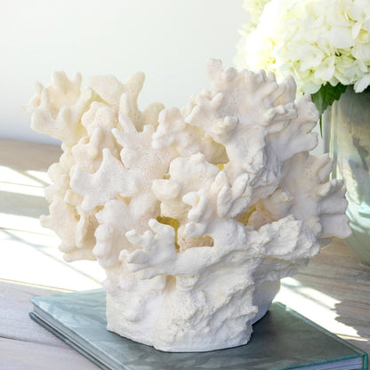 White coral sculpture on a table with a vase of flowers in the background