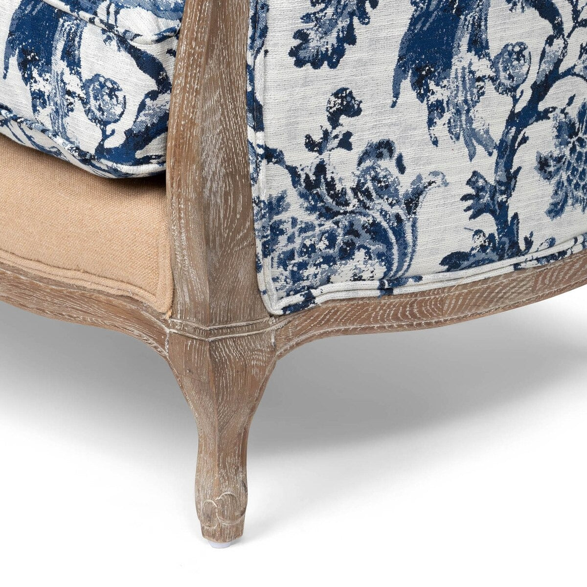 Close-up of a sofa with blue and white floral patterned cushions and wooden legs.