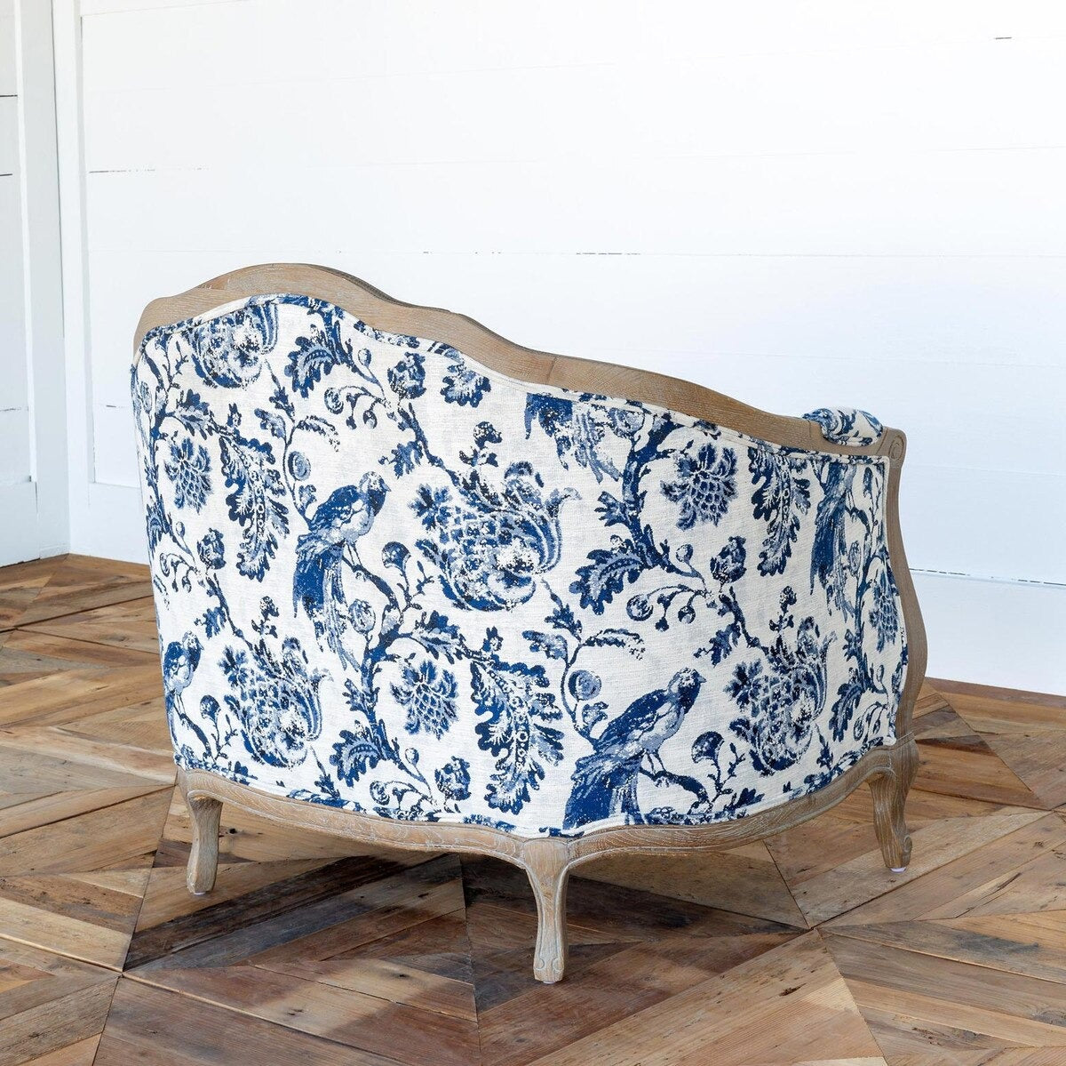 Decorative sofa with blue floral pattern on a wooden floor.