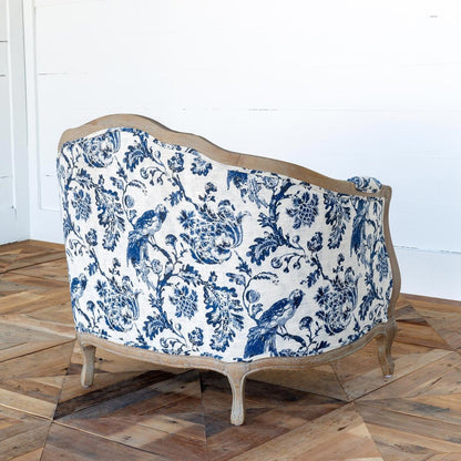 Decorative sofa with blue floral pattern on a wooden floor.