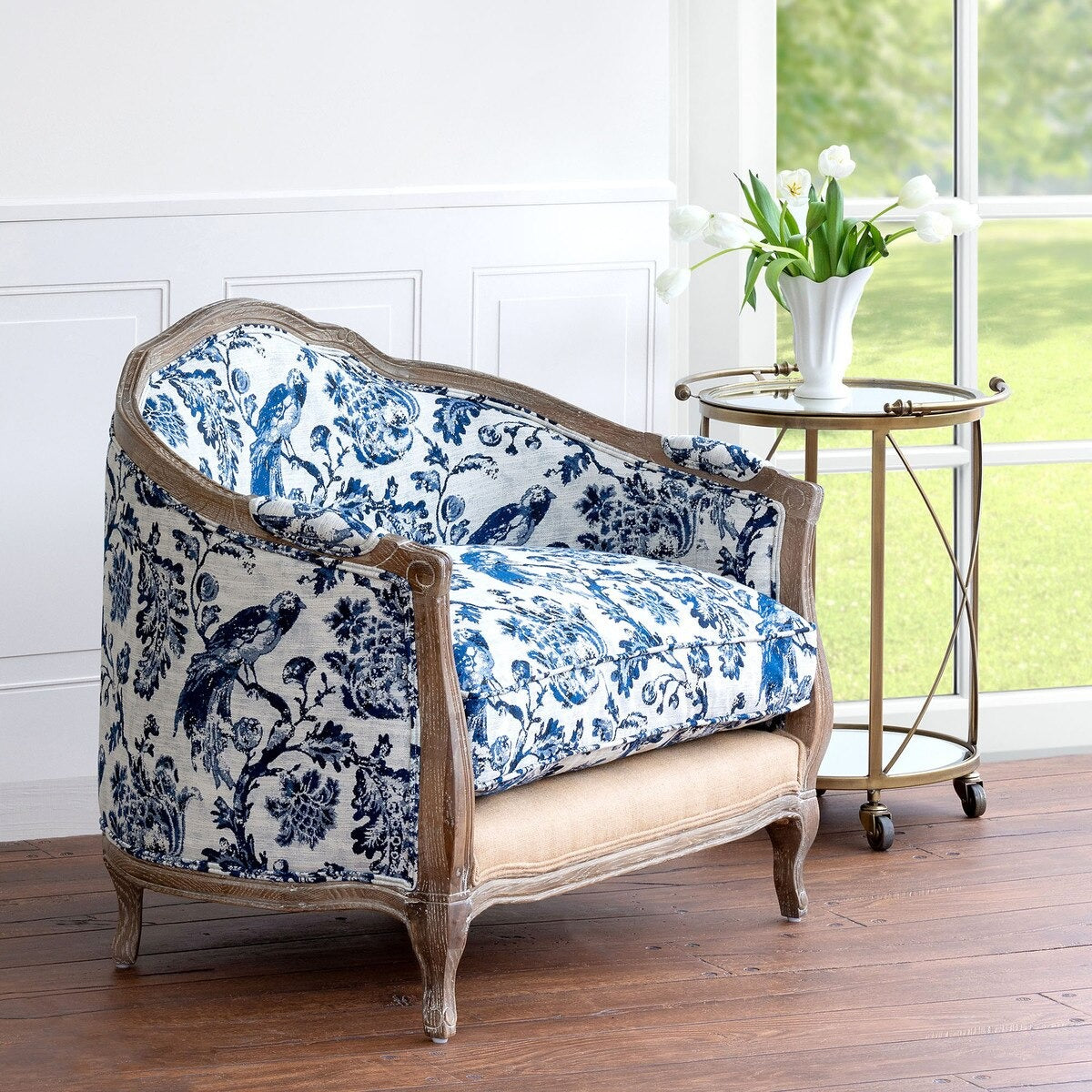 Decorative armchair with blue and white floral pattern in a room with a window and side table.