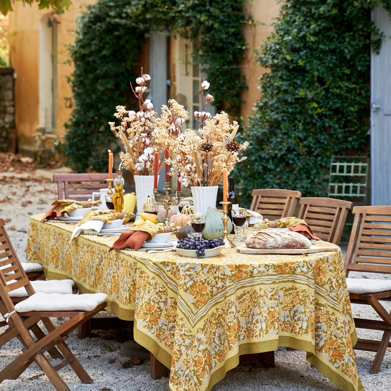 Outdoor dining table set with a floral tablecloth, candles, and decorative items.