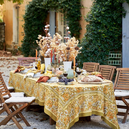 Outdoor dining table set with a floral tablecloth, candles, and decorative items.