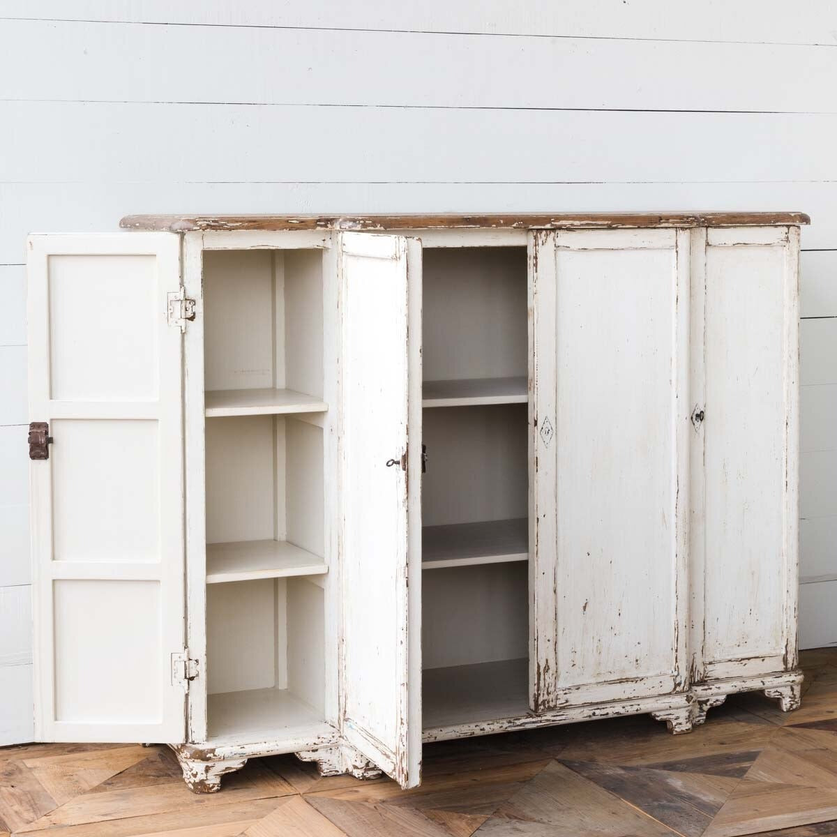 Vintage-style white cabinet with open doors on a wooden floor.