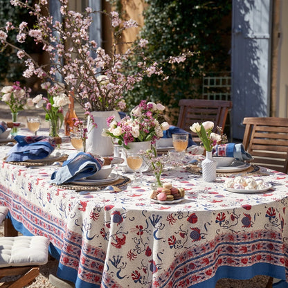Outdoor table setting with floral arrangements and patterned tablecloth