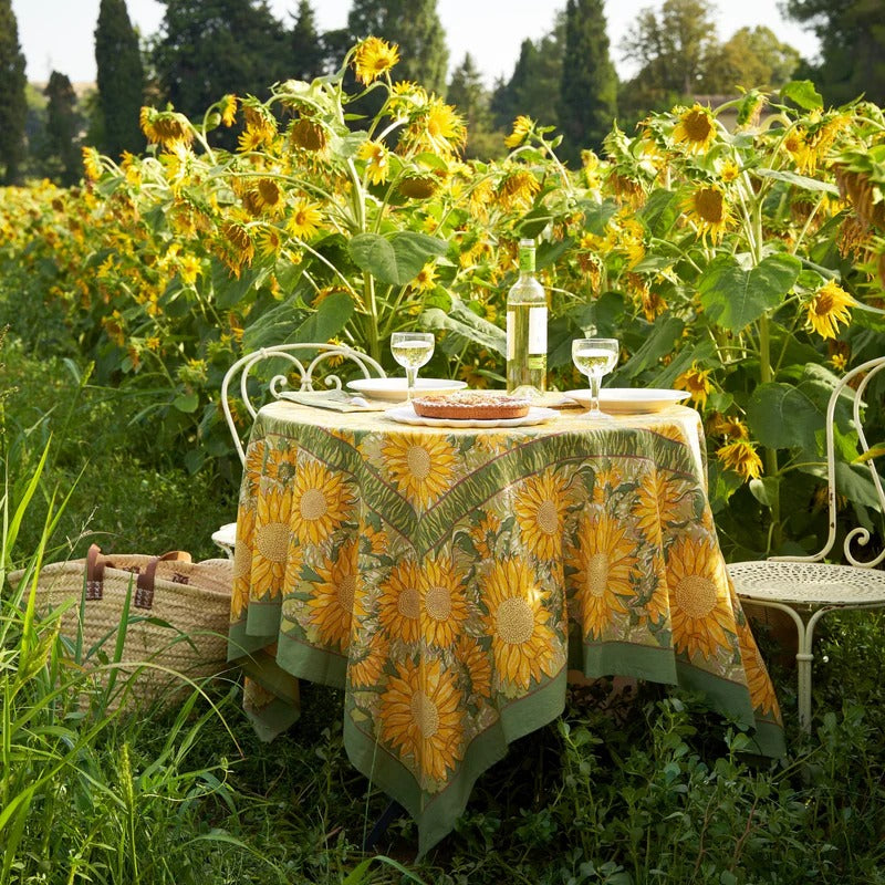 Table set with sunflower patterned tablecloth in a sunflower field